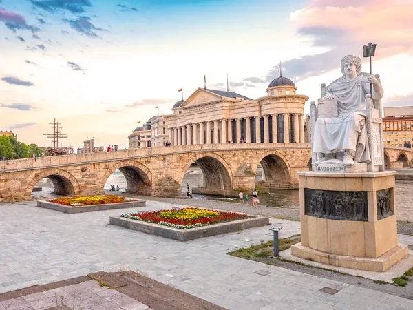 Statue des byzantinischen Kaisers Justinian und Steinbrücke, hinter dem Archäologiemuseum bei Sonnenuntergang in Skopje