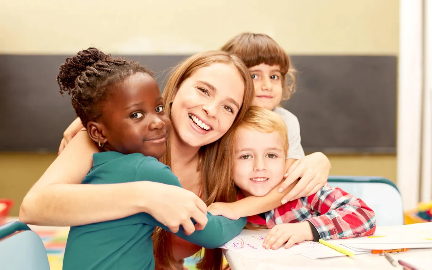 Glückliche Kinder umarmen ihre Erzieherin